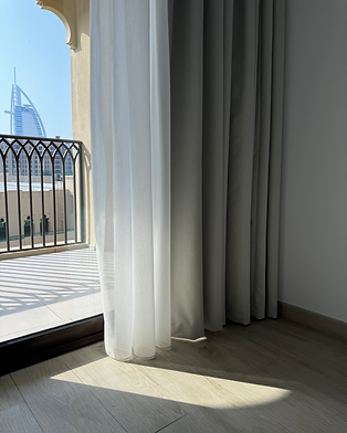 Tailored sheer and blackout curtains by a balcony window